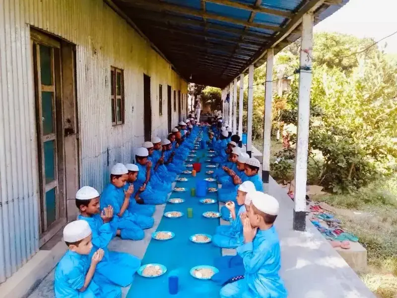 Children eating along the corridor of the original tin-shed campus in 2006